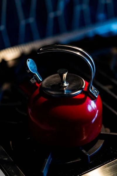 Red Tea Kettle on black stove top inside home