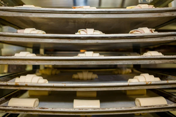 stock image Racks of uncooked pastry dough sit on stacks of cookie sheets