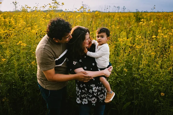 Multiracial Family Hugs Toddler Son Front Wild Flower Field — Stock Photo, Image