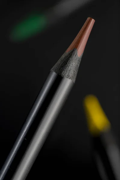 Colored pencils with a black base fly apart in a black space.