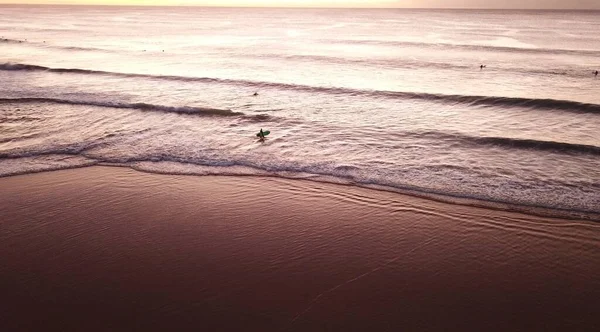 独来独往的冲浪者走进水面 带来了壮观的海洋日出 — 图库照片