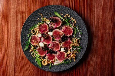 Siyah tabakta soslu mermer sığır eti carpaccio.