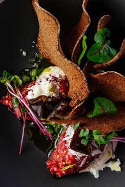 Soslu biftek ve siyah tabakta otlar.