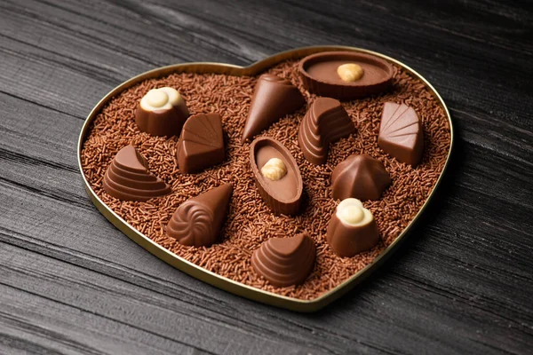 ハートボックスにチョコレートキャンディ バレンタインデーへの贈り物 暗い背景にチョコレートチップにキャンディ 休日のためのチョコレートデザート 暗い木製の背景にお菓子 チョコレートの盛り合わせ — ストック写真