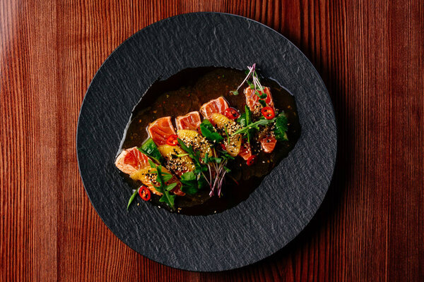 salmon carpaccio with sauce and herbs