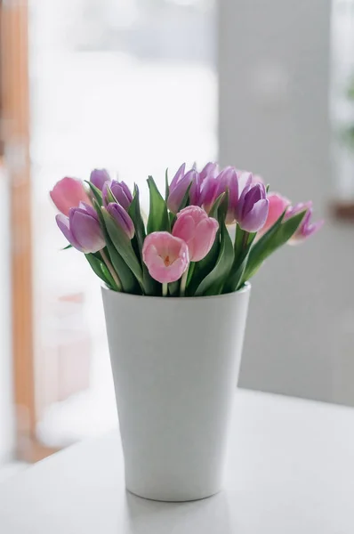 在桌上的一个白色花瓶里放着一束郁金香的花束 — 图库照片