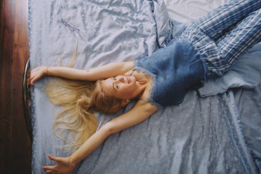 Mutlu, olgun, orta yaşlı bir kadın yatakta uzanıyor yalnız başına uyanıyor mutlu bir konsept, gülümsüyor yaşlı bayan uyanık, sağlıklı bir uykudan sonra rahat bir yatak odasında oturuyor ve günaydın.