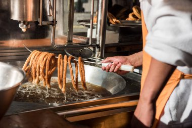 Sıcak yağdan churro çıkaran bir işçinin detaylı fotoğrafı.