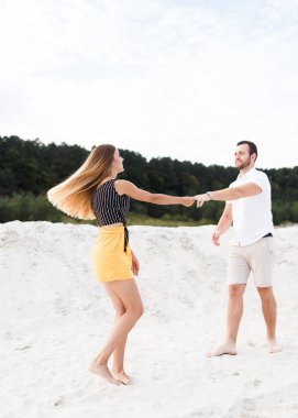 Man and woman dancing on a warm sandy beach in summer