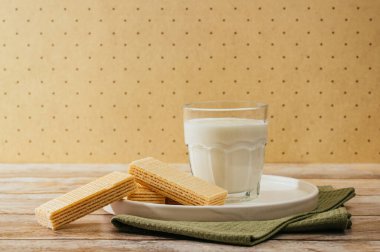 Süt bir bardakta, kremalı waffle bir tabakta tahta bir masada