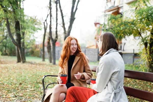 Chicas Divirtiéndose Sentado Con Bebidas Calientes Parque Otoño Banco — Foto de Stock