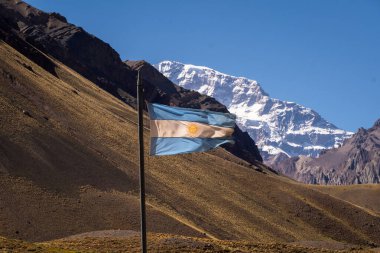 Arjantin bayrağı rüzgarda dalgalanıyor, Mendoza Arjantin 'deki Aconcagua tepesinin arkasında.