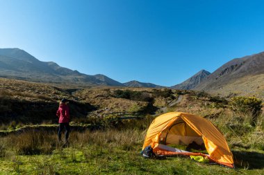 Kamp yapan gezgin kadın dağ manzarasının tadını çıkarıyor.