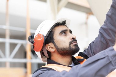 Genç teknisyen güvenlik gözlüğü ve miğfer çalışıyor.