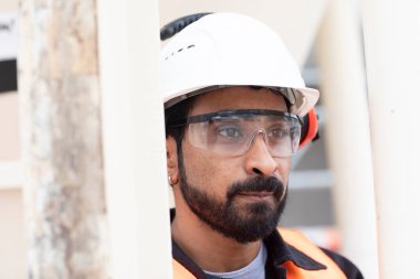 Genç teknisyen güvenlik gözlüğü ve miğfer çalışıyor.