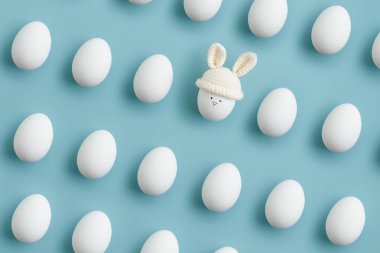 Örgü şapkalı paskalya yumurtası, mavi arka planda tavşan kulaklı. Düz yatıyordu. Yatay pankart, kartpostal