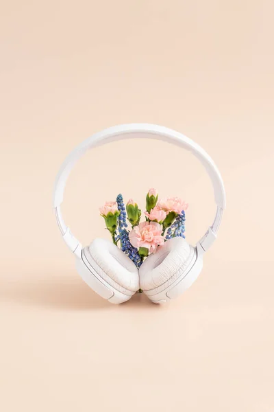 Listening music concept. White headphones with flowers.