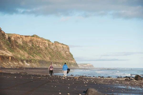 Vader Zoon Wandelen Rotsachtig Strand Met Een Surfplank — Stockfoto