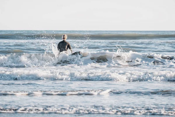 穿着湿衣的男孩和水里的冲浪板之间的距离 — 图库照片