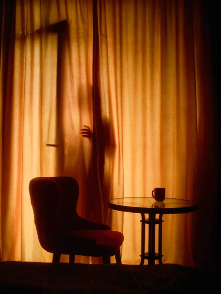 Μια Σιλουέτα Κρυφοκοιτάζει Πίσω Από Τις Κουρτίνες Ένα Σκούρο Πορτοκαλί — Φωτογραφία Αρχείου