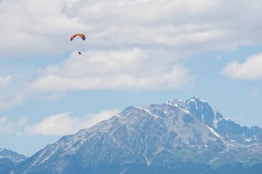 Paragliderler güneşli bir günde karla kaplı dağların üzerinde uçarlar..