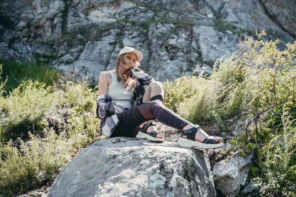 Beyaz Şapkalı Bir Kız Dağlarda Bir Taşın Üzerinde Oturuyor — Stok fotoğraf