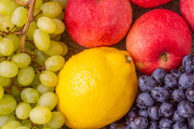 Tahta arka planda kırmızı elmalı taze üzümler.