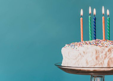 Beyaz kremalı doğum günü pastası ve mavi arka planda mumlar.