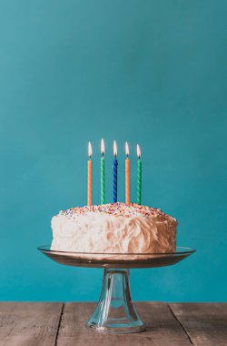 Beyaz kremalı doğum günü pastası ve mavi arka planda mumlar.