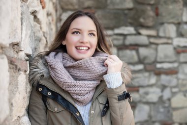 Taş duvarın yanında gülen genç kadın