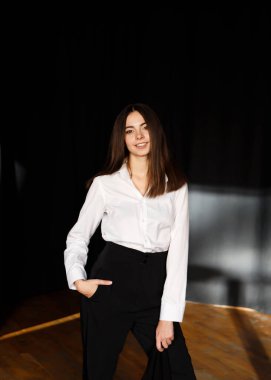 Prova salonunda beyaz gömlekli ve siyah pantolonlu bir aktris.