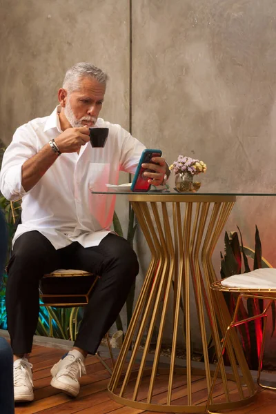 コーヒーとスマートフォンを持つシニア男性 — ストック写真
