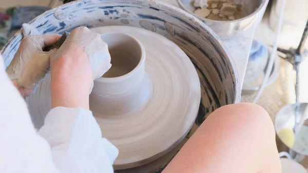 陶芸家の車輪の後ろに座っている若い陶芸家の女性 手工芸品の生産 陶器作り — ストック写真