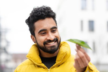 Elinde yeşil bir yaprak tutan genç bir adam.