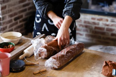 Kırmızı kille çalışan genç bayan çömlekçi çömlek yontmaya hazırlanıyor.