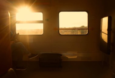 Trenle seyahat eden bir iş adamı. İş seyahati sırasında rahat koltukta oturan rahat giyimli yolcu kısa mesafe toplu taşıma kavramı. Yüzü yok. Pencereden geçen güneş ışığı.