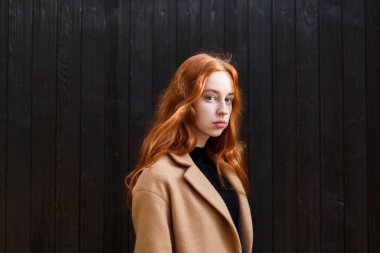 Sonbaharda evinin yanında paltolu, kızıl saçlı genç bir kadın.