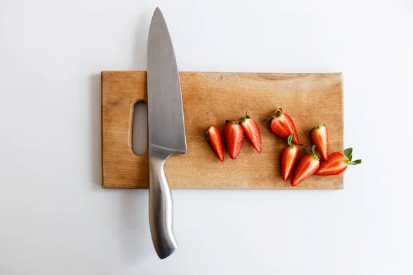 イチゴのナイフは台所の木のまな板の上にある — ストック写真