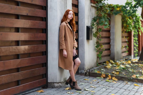 秋に家の近くにコートを着た若いスタイリッシュな赤い髪の女性 — ストック写真