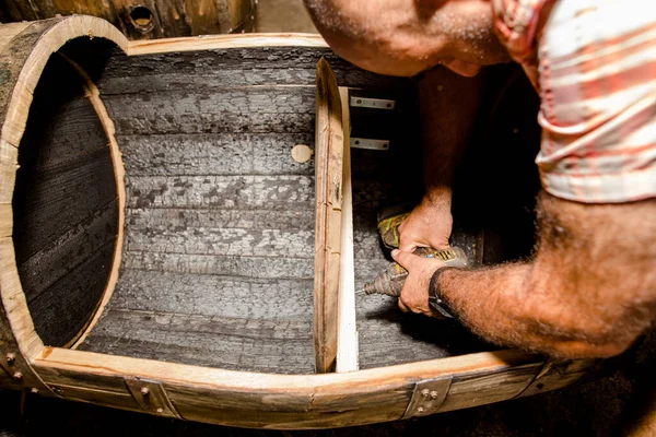 A furniture maker assembles a wooden shelf with an electric drill