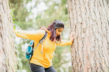 Sırt çantasıyla ağaca tırmanan genç bir kadın.