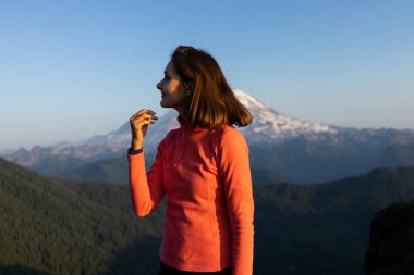 Kadın yürüyüşçü Rainier Dağı Ulusal Parkı, Wash 'ta gün batımına bayılıyor.