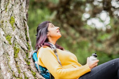 Genç bir kadın bir ağacın dalında yürüyor ve dinleniyor.