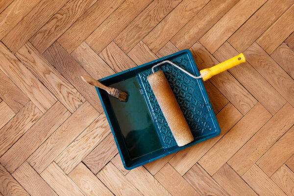brush and roller in container with varnish during varnishing parquet