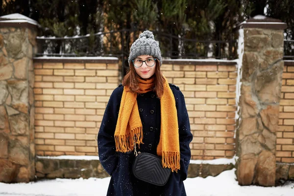 雪の通りの真ん中にある黄色のスカーフと青いコートの女性 — ストック写真
