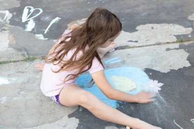 Tebeşirle çizen kız, yaratıcılığa dalmış..