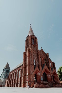 Red sandstone church against bright blue sky clipart