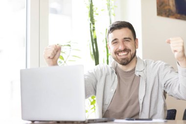 Sakallı bir adam ofiste çalışıyor ve kazanan imzaları atıyor.