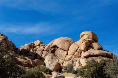 Rounded boulders stack under blue sky in Joshua Tree clipart