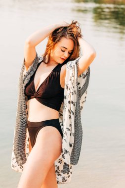 Nehirde siyah bikini ve bornoz giymiş 29 yaşında güzel bir kadın.